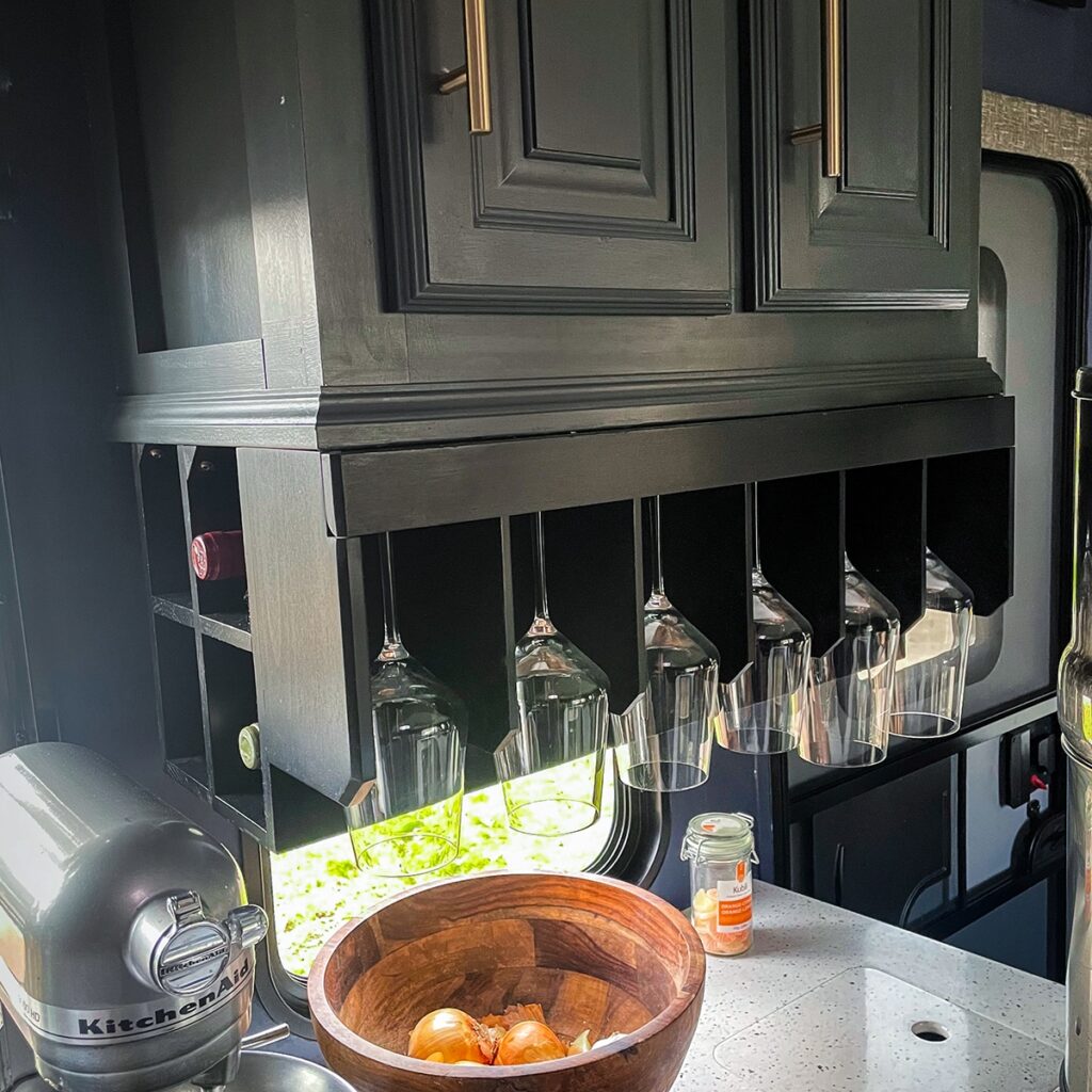 RV kitchen area with hanging glasses.